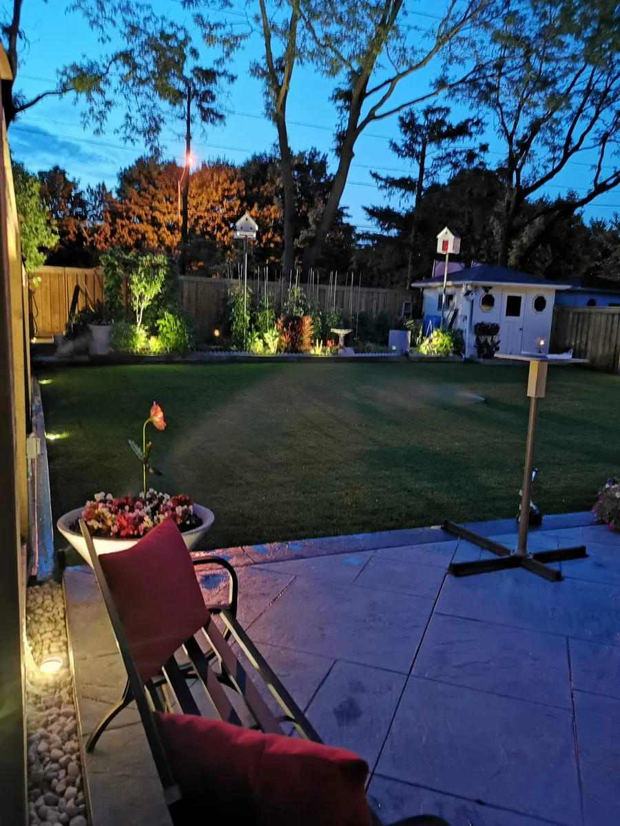 Backyard garden lighting at dusk seen from a stone patio
