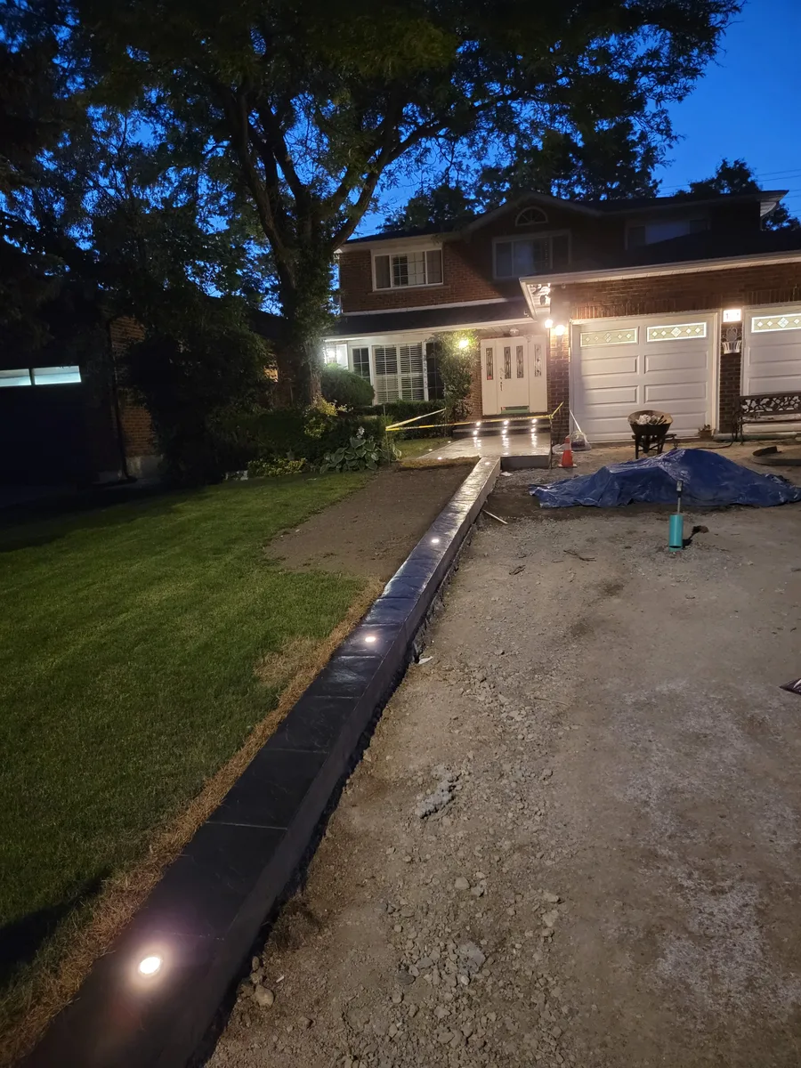 Curb lights installed along a new driveway edge with the lawn already down