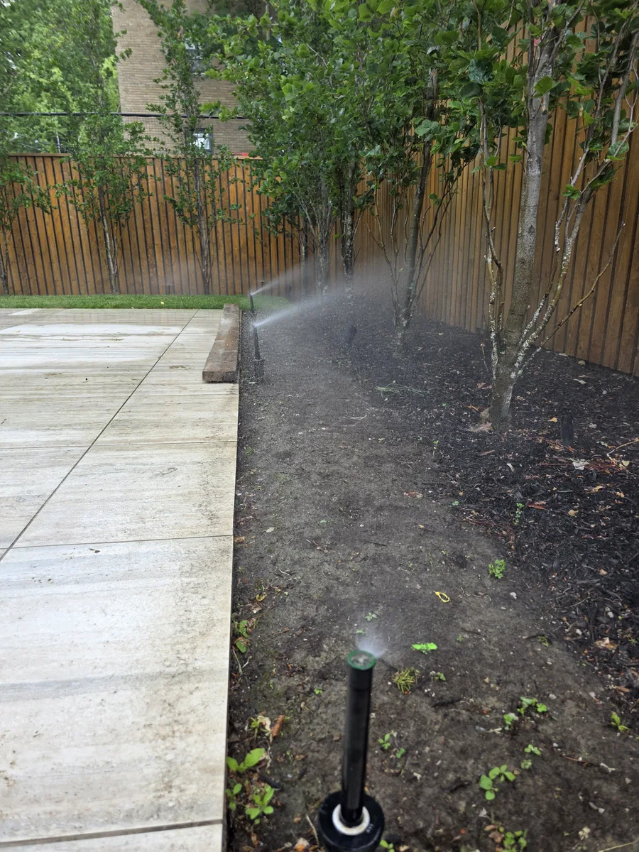 Irrigation zone running in a garden bed next to a stone patio