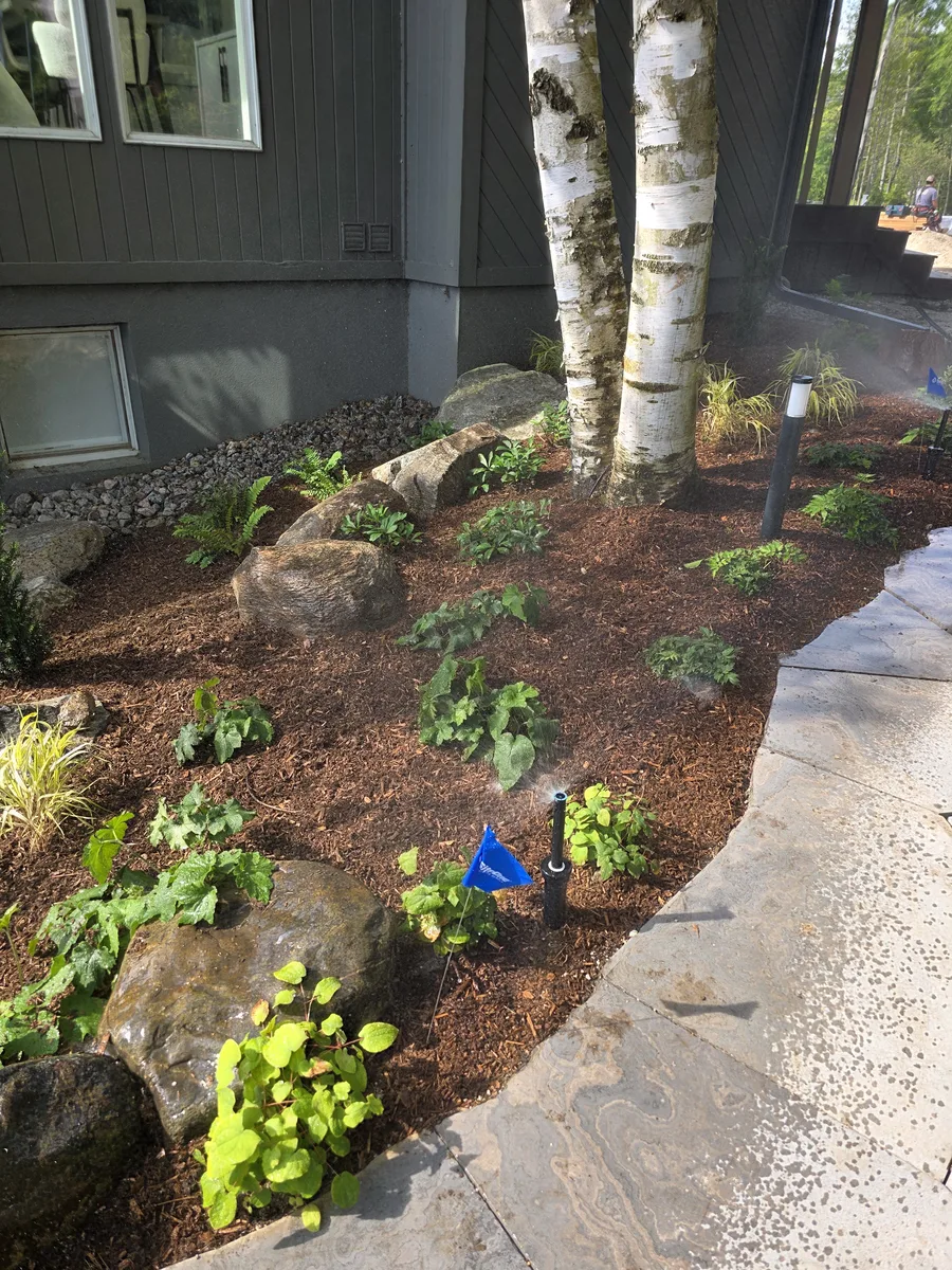 New irrigation installed in a planting bed beside a stone patio