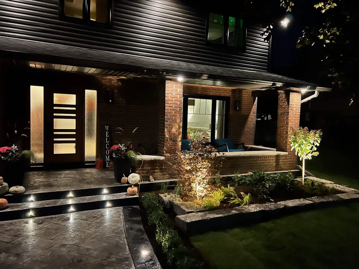 Uplighting on a planted garden bed beside a front porch at night